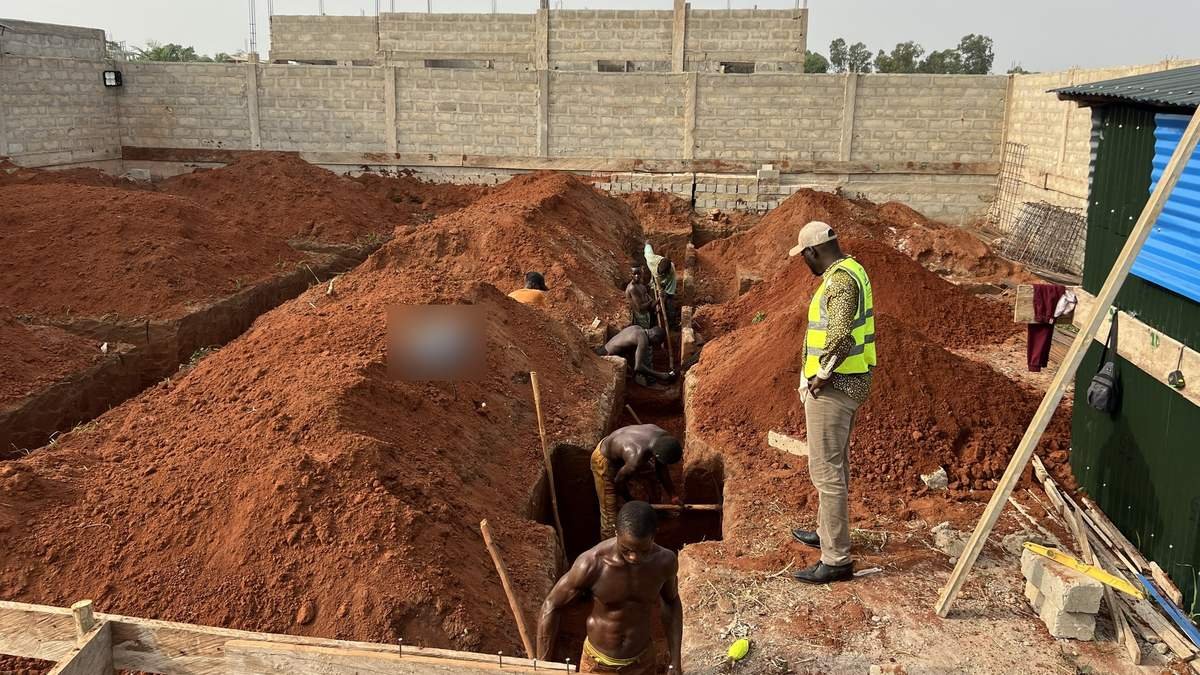 Chantier de villa à Cotonou : tranchées de fondations creusées dans la terre rouge sous le regard du superviseur
