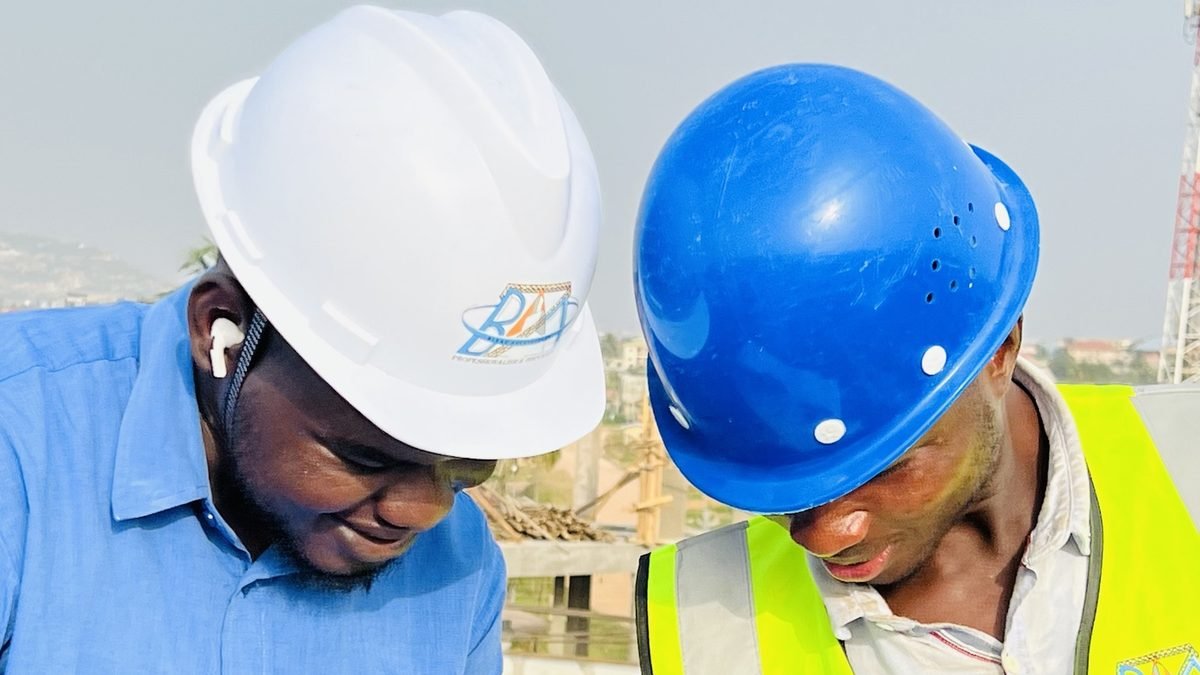 Deux professionnels casqués de BLEAZ Architecture penchés sur un plan sur un chantier